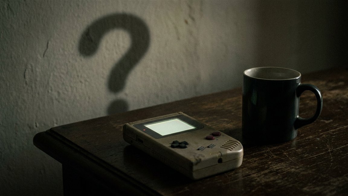 Handheld console on a table with a question mark-shaped shadow